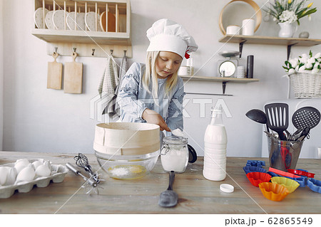 Little girl in a white shef hat cook the dough for cookies Little girl in a white shef hat cook the dough for cookies 62865549