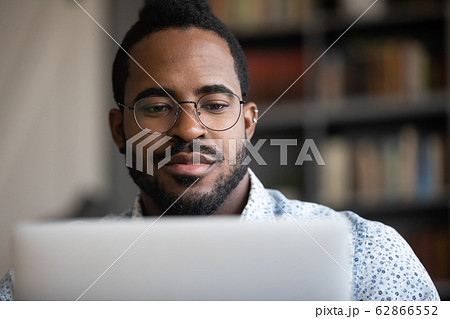 Close up focused young african ethnicity man working on computer. Close up focused young african ethnicity man working on computer. 62866552