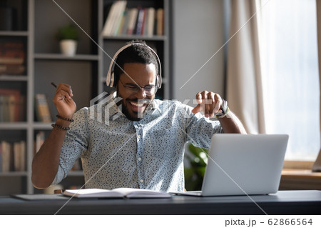 Happy young african american businessman enjoying listening energetic music. Happy young african american businessman enjoying listening energetic music. 62866564