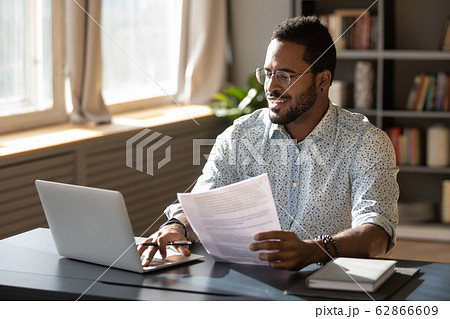 Happy millennial african american businessman in eyewear doing paperwork. Happy millennial african american businessman in eyewear doing paperwork. 62866609