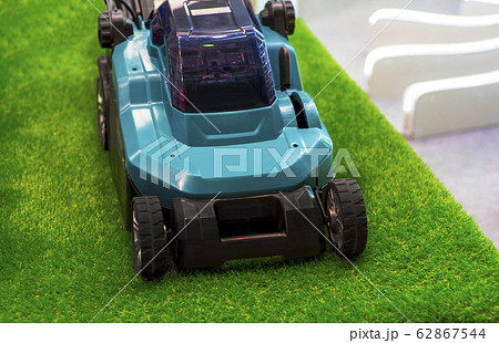 Turquoise lawn mower on grass Turquoise lawn mower on grass 62867544