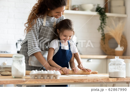 Young mom and little daughter baking in kitchen together 62867990