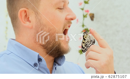 male holds a butterfly in his hand and wants to eat an insect, joke, close-up male holds a butterfly in his hand and wants to eat an insect, joke, close-up 62875107