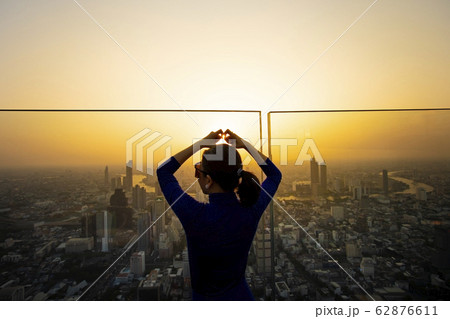 woman making heart shape by finger standing on 62876611