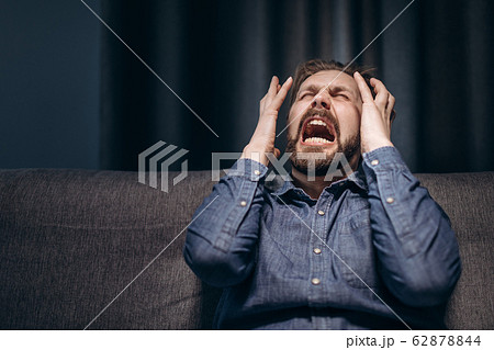 Portrait of bearded man screaming desperately in dark 62878844