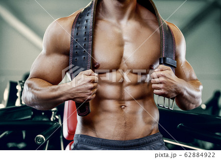 Bodybuilder strong man pumping up abs muscles 62884922