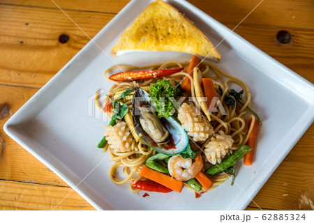 Seafood spaghetti, shrimp, squid, vegetables Asian cuisine is popular on white plates on wooden floors. Seafood spaghetti, shrimp, squid, vegetables Asian cuisine is popular on white plates on wooden floors. 62885324