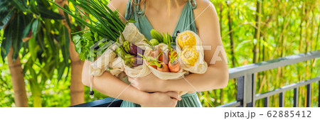 Set of fresh vegetables in a reusable bag in the hands of a young woman. Zero waste concept BANNER Set of fresh vegetables in a reusable bag in the hands of a young woman. Zero waste concept BANNER 62885412
