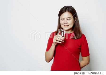 Young beautiful woman drinks water from a glass 62886116
