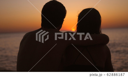 Romantic couple relaxing enjoying on beach looking at sunset 62886187