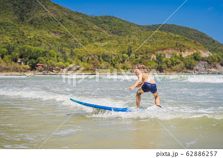 Healthy young boy learning to surf in the sea or ocean Healthy young boy learning to surf in the sea or ocean 62886257