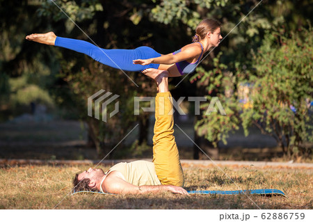 Acroyoga couple balancing on feet in the park 62886759