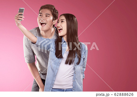 Asian couples making a selfie with a funny face using a camera phone Asian couples making a selfie with a funny face using a camera phone 62888626