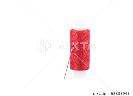 Close-up photo of a spool with red thread and a needle isolated over white background. Close-up photo of a spool with red thread and a needle isolated over white background. 62888943