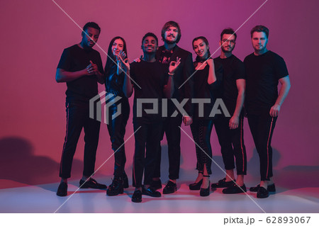 Group of young multiethnic musicians created band, dancing in neon light on pink background Group of young multiethnic musicians created band, dancing in neon light on pink background 62893067