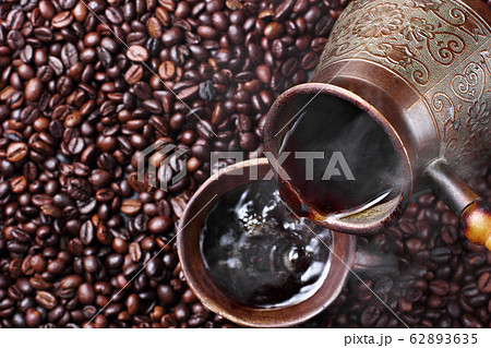 Pouring turkish coffee into clay cup. Pouring turkish coffee into clay cup. 62893635