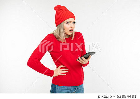 pensive excited girl with a phone in her hands on a white background with copy space pensive excited girl with a phone in her hands on a white background with copy space 62894481
