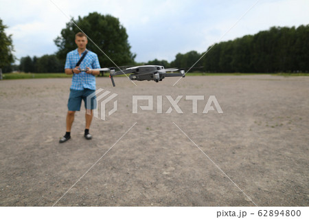 In foreground drone flies, guy controls drone In foreground drone flies, guy controls drone 62894800