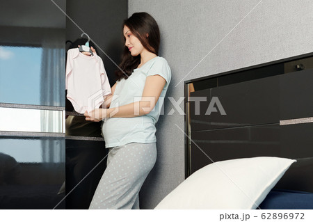 Pregnant woman preparing baby clothes Pregnant woman preparing baby clothes 62896972