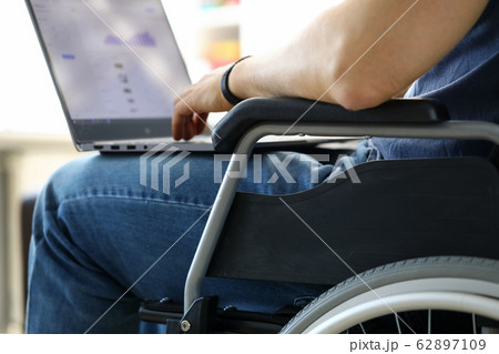 Man sitting in wheelchair working with laptop computer 62897109