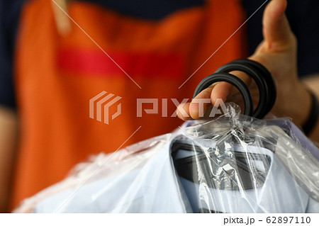 Clothes dry cleaning service worker returning shirts to customer Clothes dry cleaning service worker returning shirts to customer 62897110