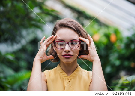 Tired young woman standing in greenhouse in botanical garden. 62898741