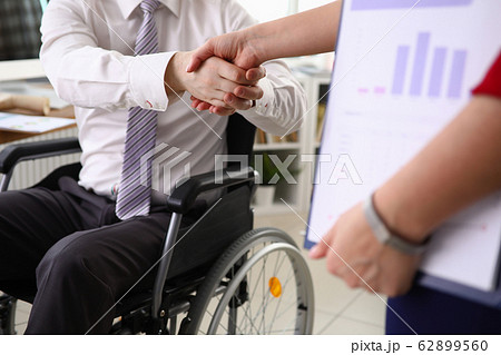 Man in suit sits in wheelchair and shakes his hand Man in suit sits in wheelchair and shakes his hand 62899560
