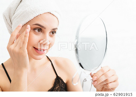 Millennial woman massaging her face, looking at mirror Millennial woman massaging her face, looking at mirror 62901915