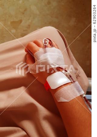 Blurred image of a patient hand with iv tube for blood transfusion in close-up. Blurred image of a patient hand with iv tube for blood transfusion in close-up. 62903264