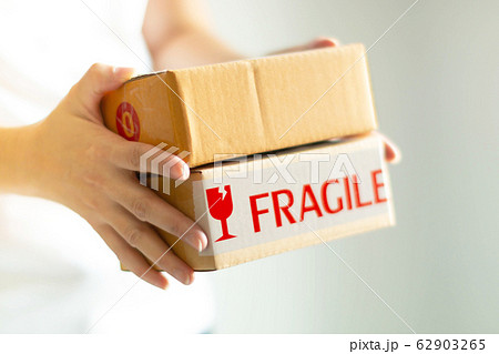 Close-up image of two hands holding two parcel boxes on white background; selective focus. Close-up image of two hands holding two parcel boxes on white background; selective focus. 62903265