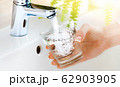 Close up pouring purified drink water from the tap or faucet in bathroom. Clear water cup in woman hand 62903905