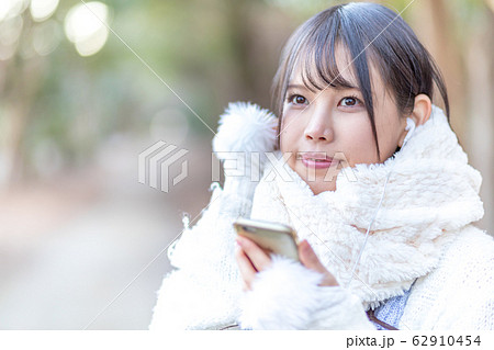スマートフォンで音楽を聴く若い女性 屋外 冬 スマートフォンで音楽を聴く若い女性 屋外 冬 62910454