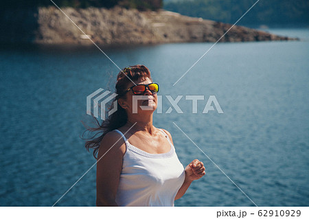 the girl is sitting on the rocks by the lake. Woman sunbathing on the beach. The concept of recreation, tourism 62910929