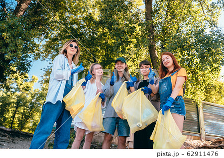 Group of activists friends collecting plastic waste on the beach. Guys show thumb up. 62911476