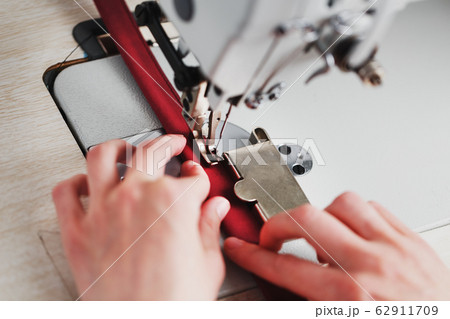 A leather craftsman produces leather goods on a 62911709