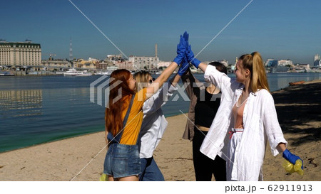Group of activists friends collecting plastic waste on the beach. Environmental conservation. 62911913