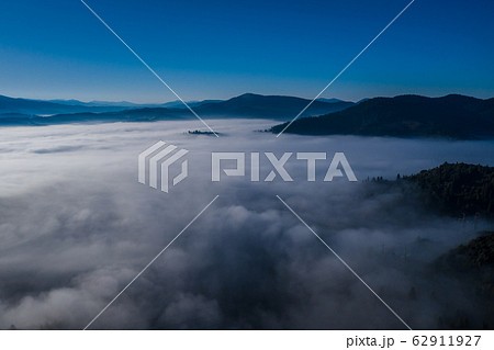 Aerial view of colorful mixed forest shrouded in morning fog on a beautiful autumn day Aerial view of colorful mixed forest shrouded in morning fog on a beautiful autumn day 62911927