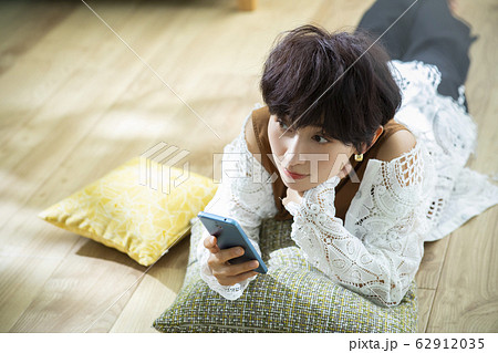 女性　ショートヘア　寝転ぶ　スマホ　スマートフォン 62912035
