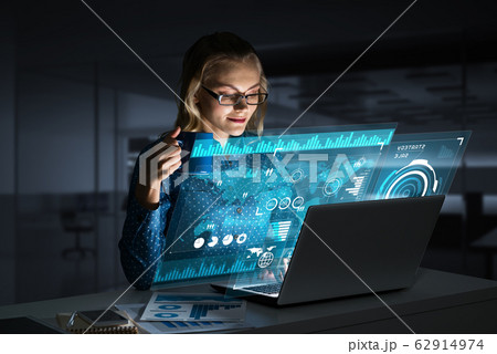 Beautiful blonde working on laptop and infographs out of screen. Mixed media 62914974