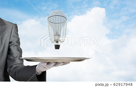 Hand of waiter presenting balloon on tray. 62917948
