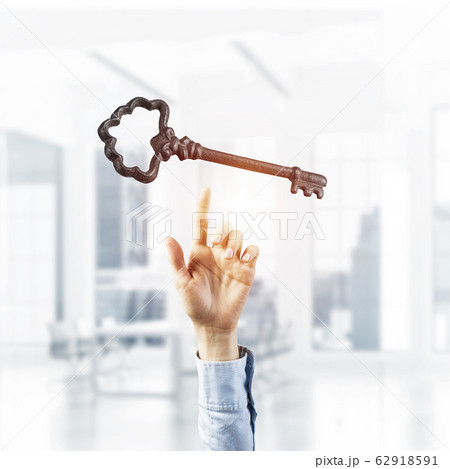 Retro metal key and male palm against office interior. Mixed med 62918591