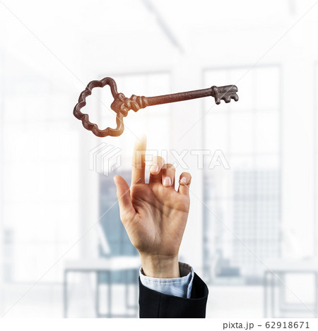 Retro metal key and male palm against office interior. Mixed med 62918671