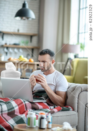 Dark-haired young man laying on the sofa feeling sick Dark-haired young man laying on the sofa feeling sick 62922329
