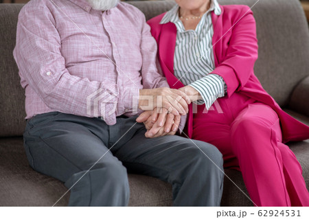 Husband and wife sitting on the sofa holding each others hands 62924531