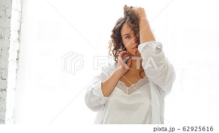 Sexy young woman in white shirt in bedroom - white light from window 62925616