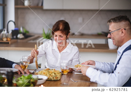 Group of senior friends at dinner party at home, eating. 62925781