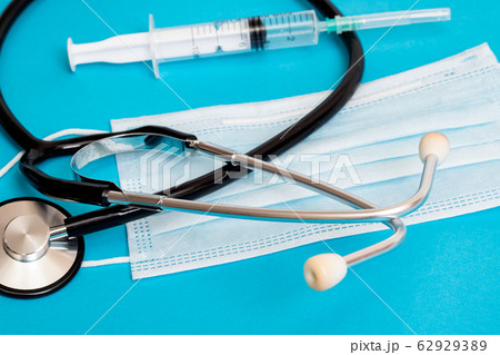 Stethoscope, protective mask and syringe on blue 62929389
