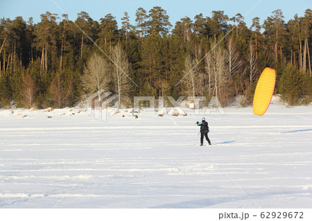 Man is engaged in snowkiting on the snowy surface Man is engaged in snowkiting on the snowy surface 62929672