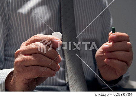 businessman with a pill, hands close view - 62930704