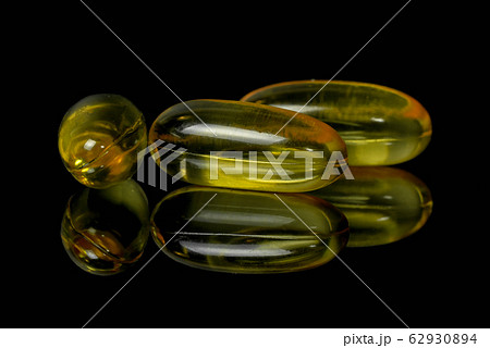three fish oil capsules on a black mirror surface three fish oil capsules on a black mirror surface 62930894